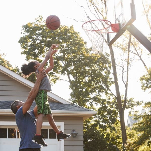 Dad raising daughter up to make a basketball shot